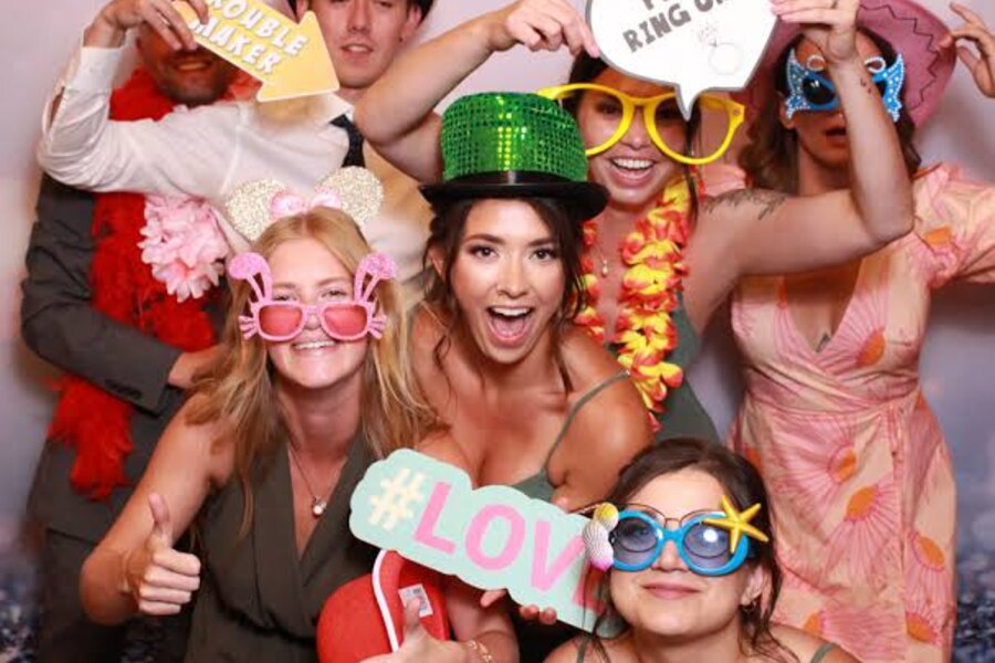 Group of guests posing together with colorful photobooth props
